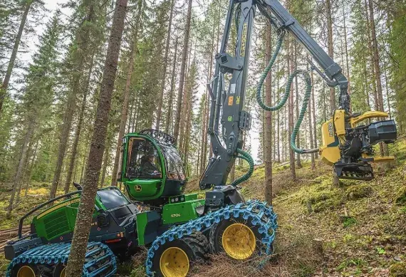 Tracked forestry harvester operating on a wooded slope